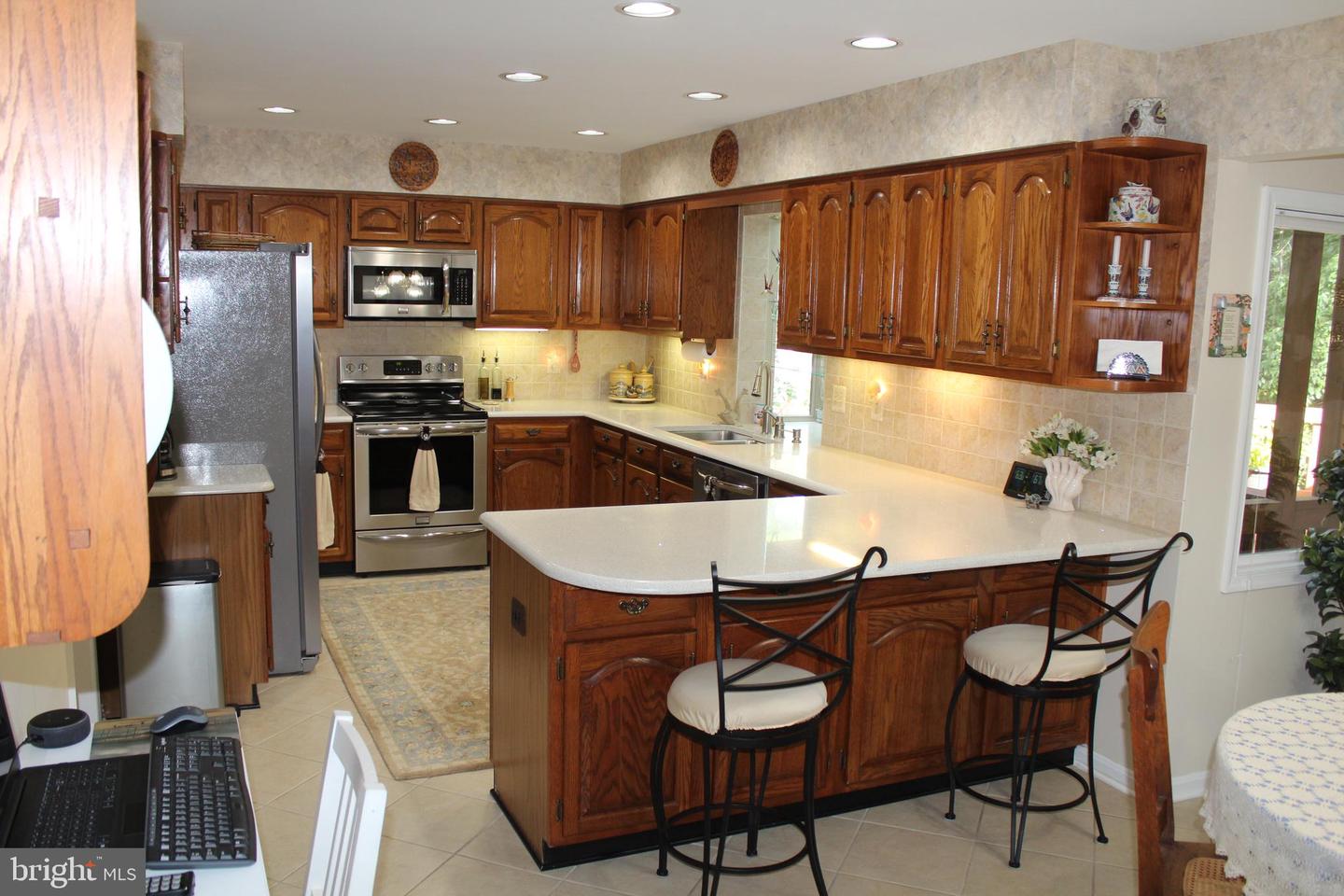 Kitchen with dark wood cabinets, stainless appliances, and a large white island with bar stools.