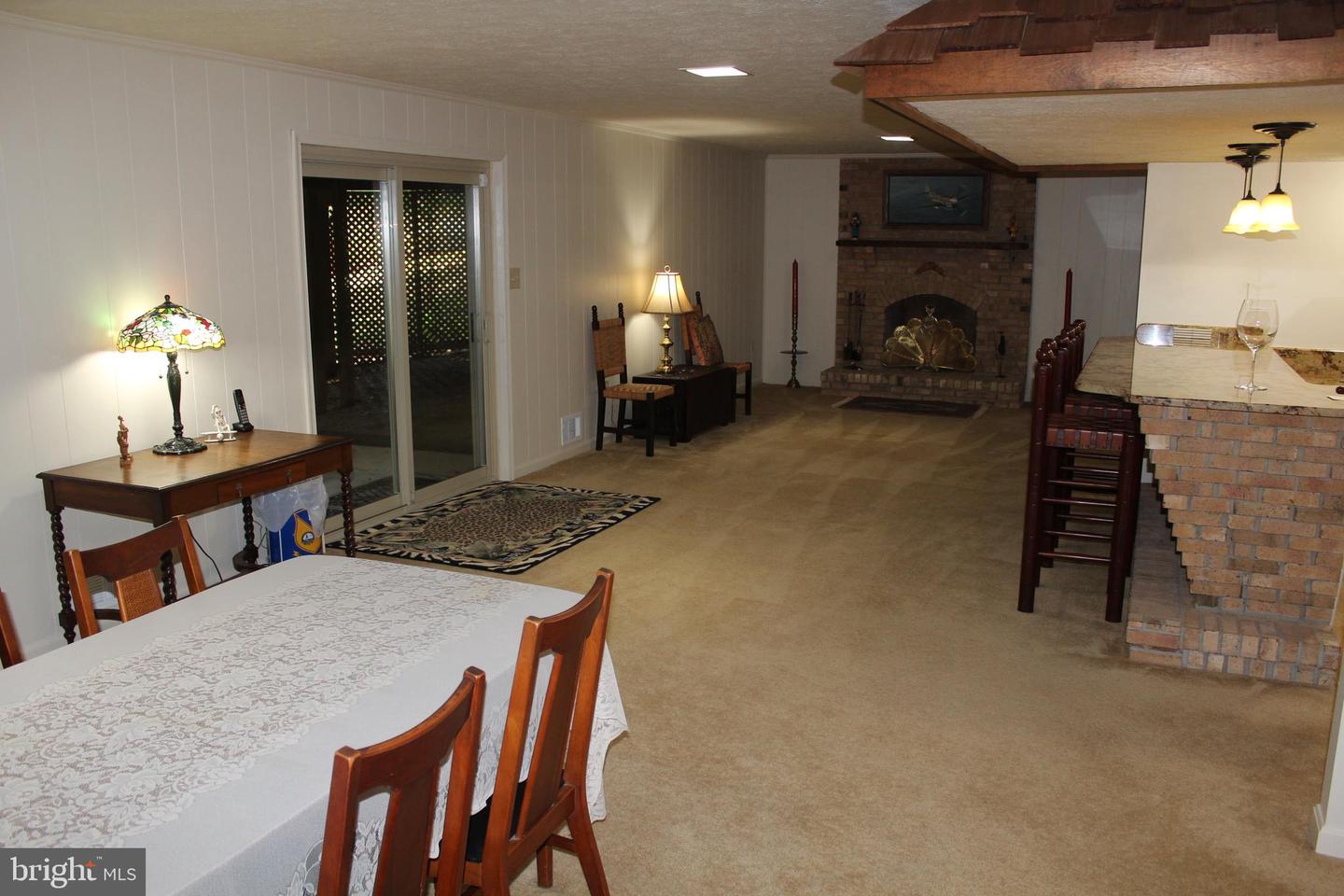 Dining and living area with a brick fireplace, breakfast bar, and sliding glass doors.