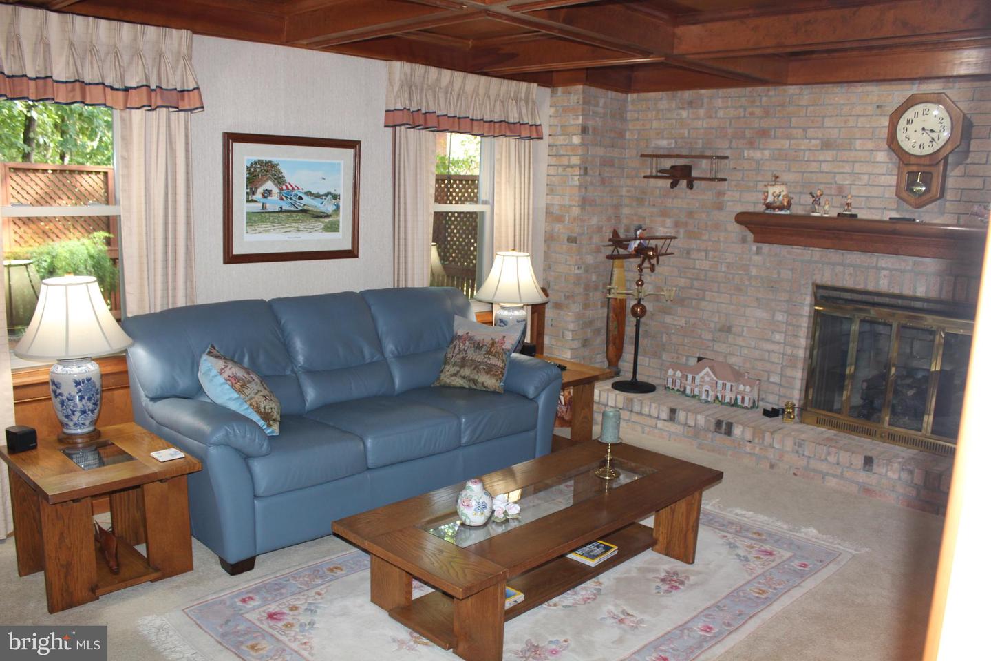 Furnished living room with blue leather sofa, brick fireplace, and wood-paneled ceiling.