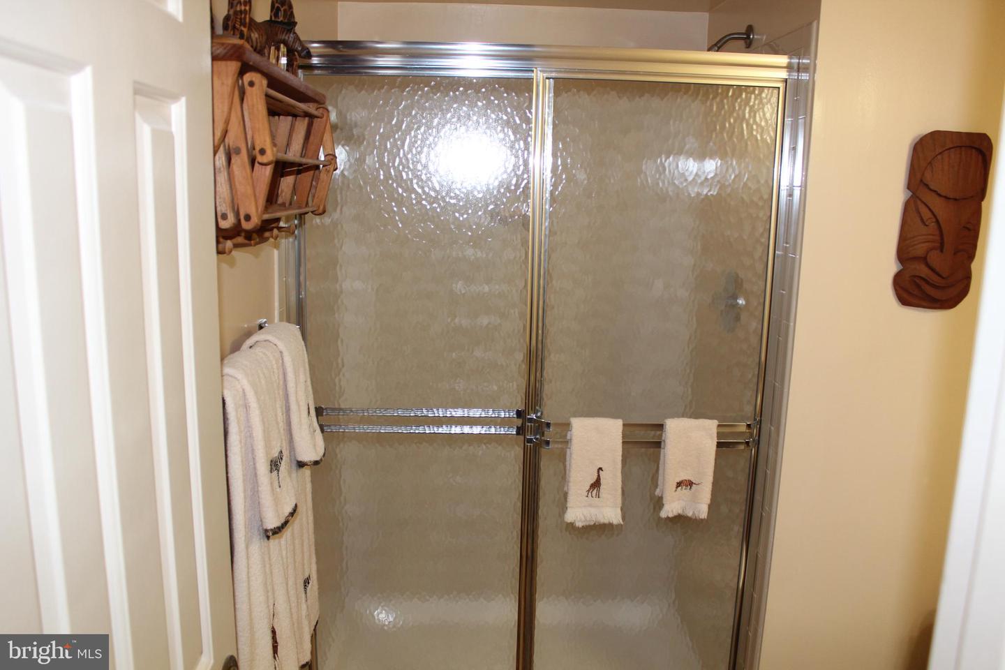 Bathroom shower with textured glass doors, chrome framing, and towels hanging nearby.