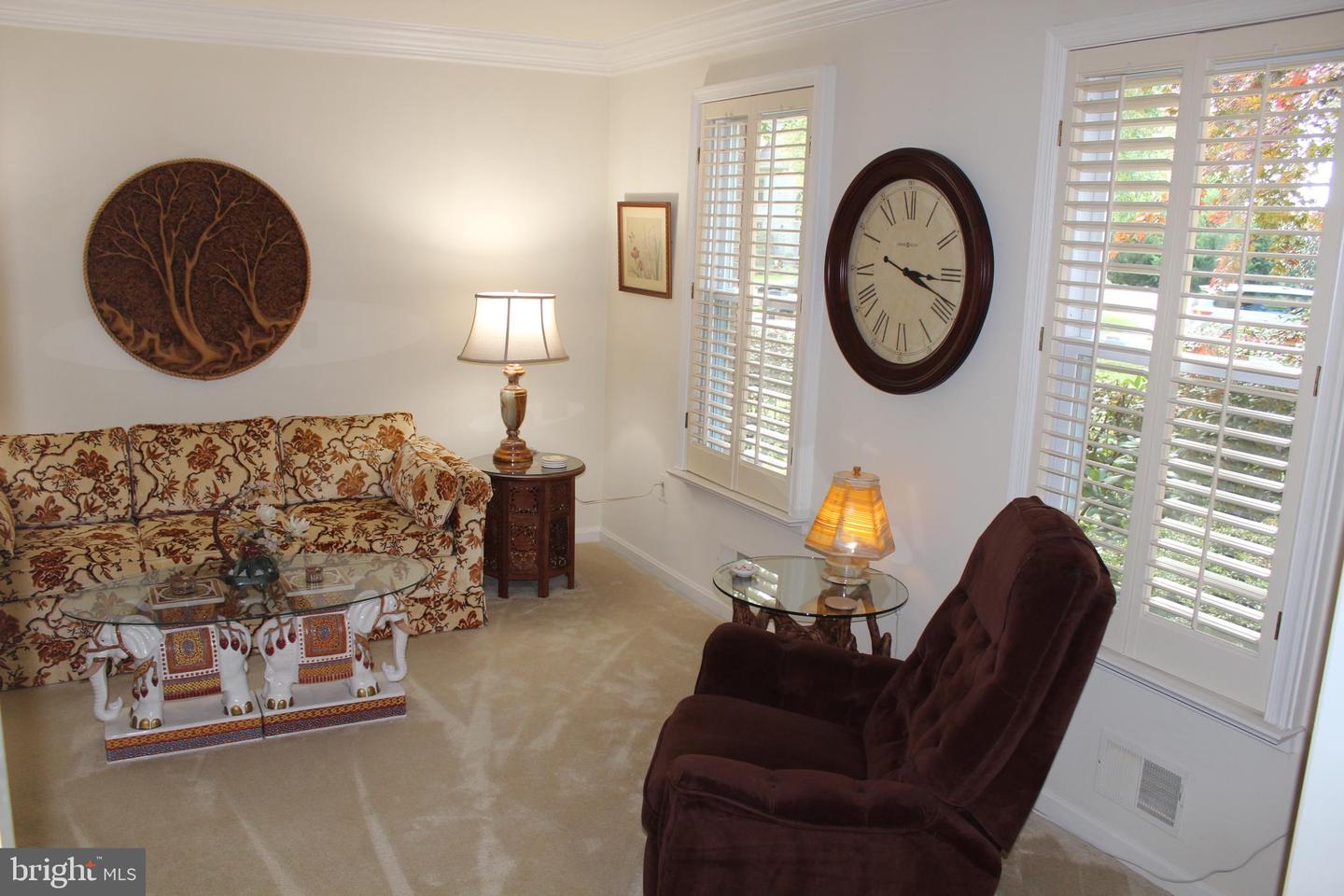 Furnished living room with a patterned sofa, dark recliners, and plantation shutters.
