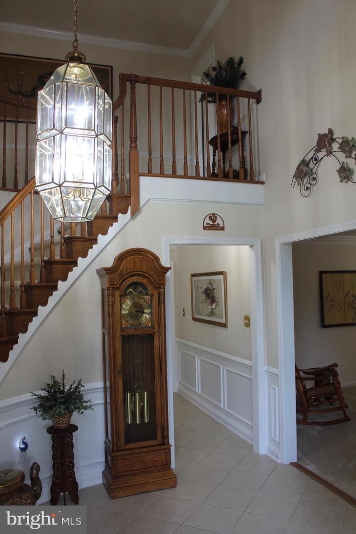 Two-story foyer with a wooden staircase, hanging glass lantern, and grandfather clock.