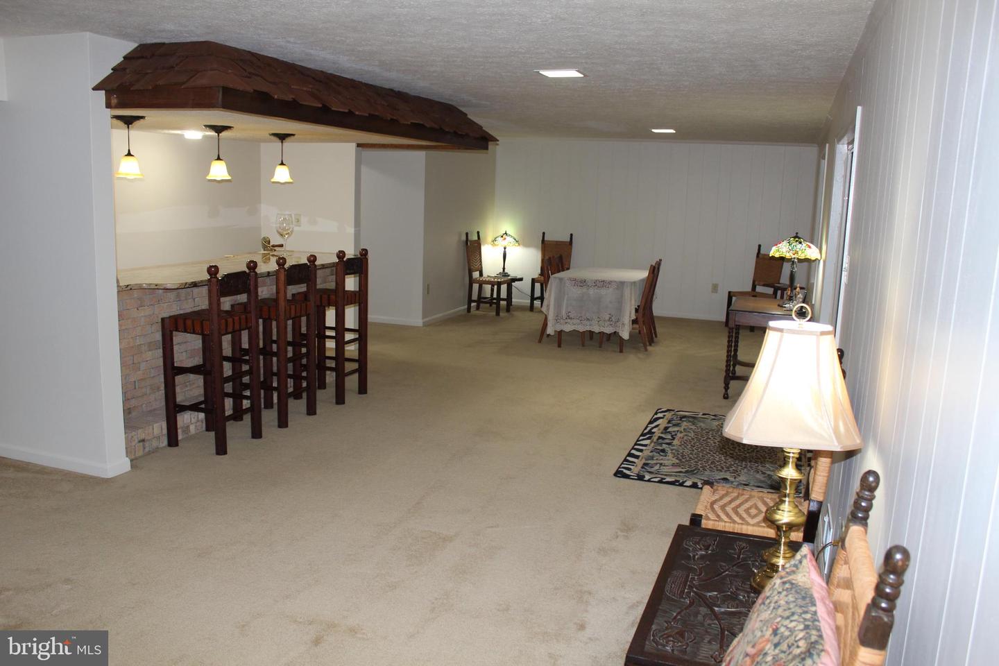 Furnished recreation room with a brick-front bar, wooden stools, and a dining table.