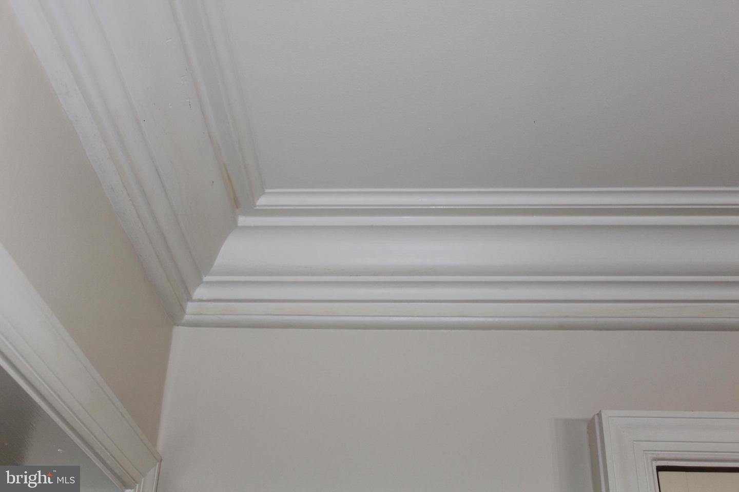 White crown molding and decorative trim at a ceiling corner, with part of a doorway visible.
