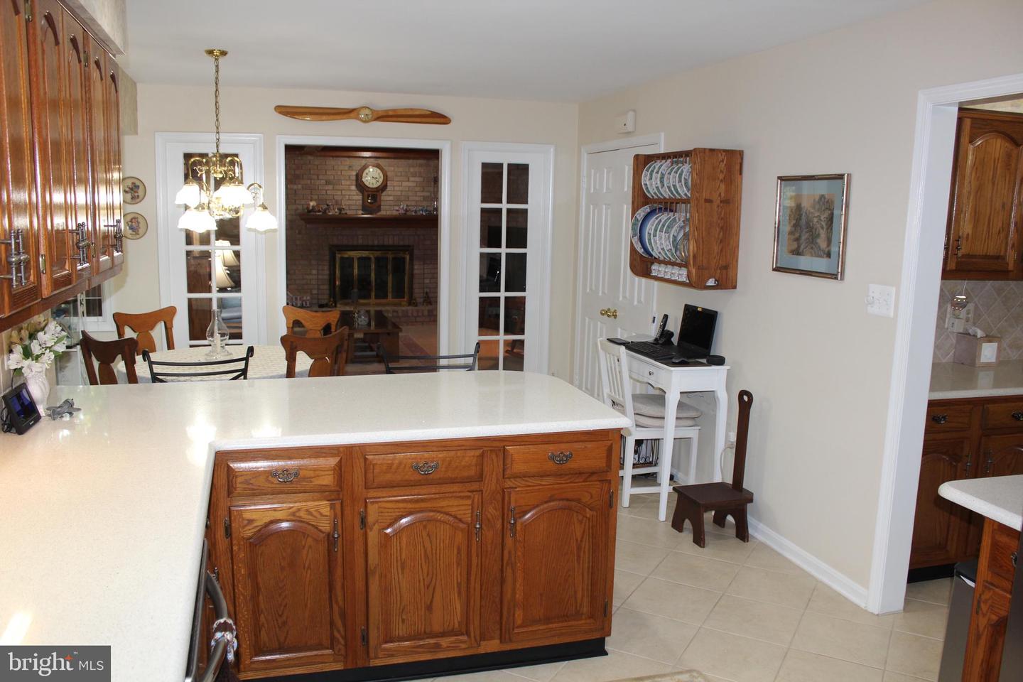 Kitchen with a large white island, oak cabinetry, and a brick fireplace visible beyond.