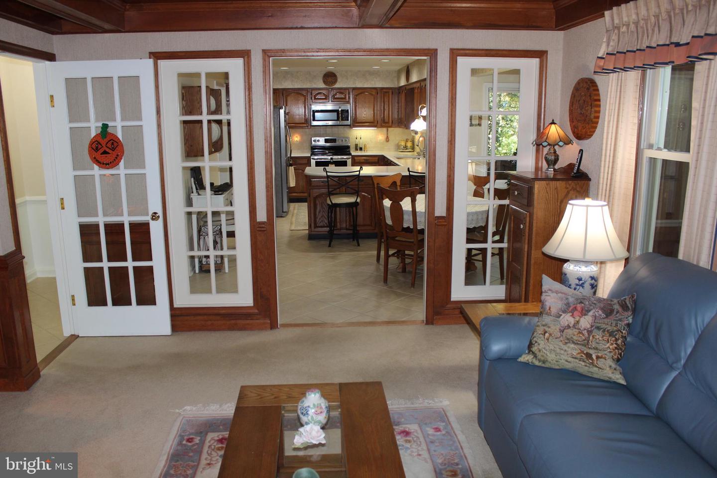Living room with a blue leather sofa and French doors opening to a wood-cabinet kitchen.