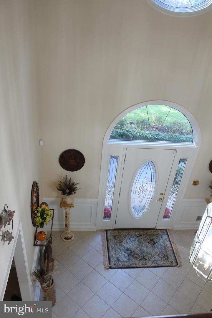 Foyer with a glass-paneled front door, arched transom window, tiled floor, and patterned rug.