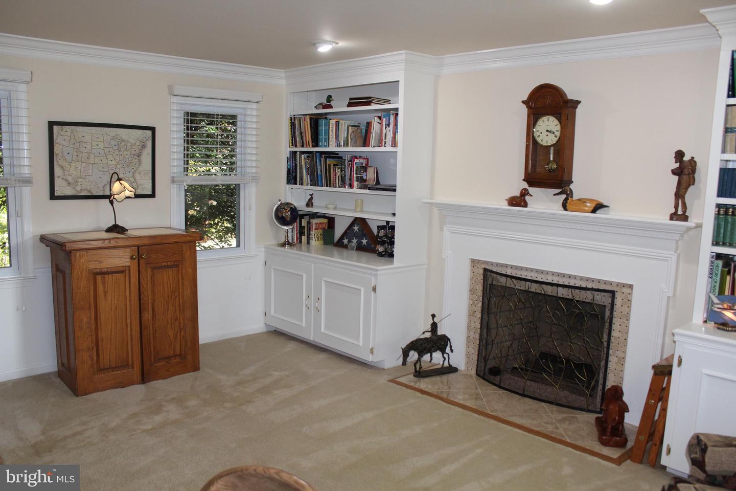 Living room with a white fireplace, built-in bookshelves, and a wooden cabinet beneath the window.
