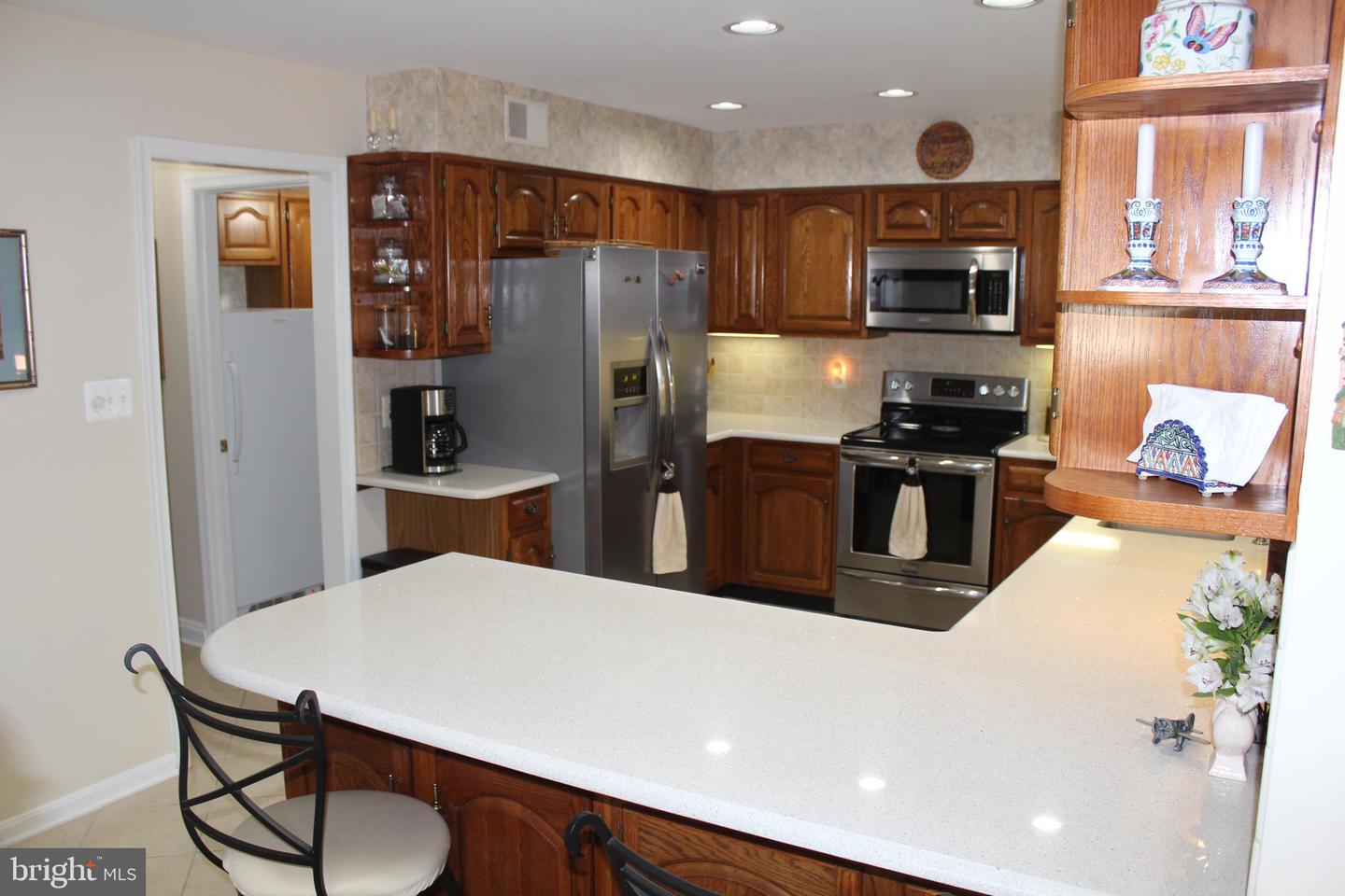 Kitchen with dark wood cabinets, stainless steel appliances, and a spacious breakfast bar.