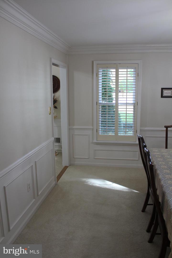 Dining room with paneled wainscoting, a shuttered window, and part of a table and chairs.