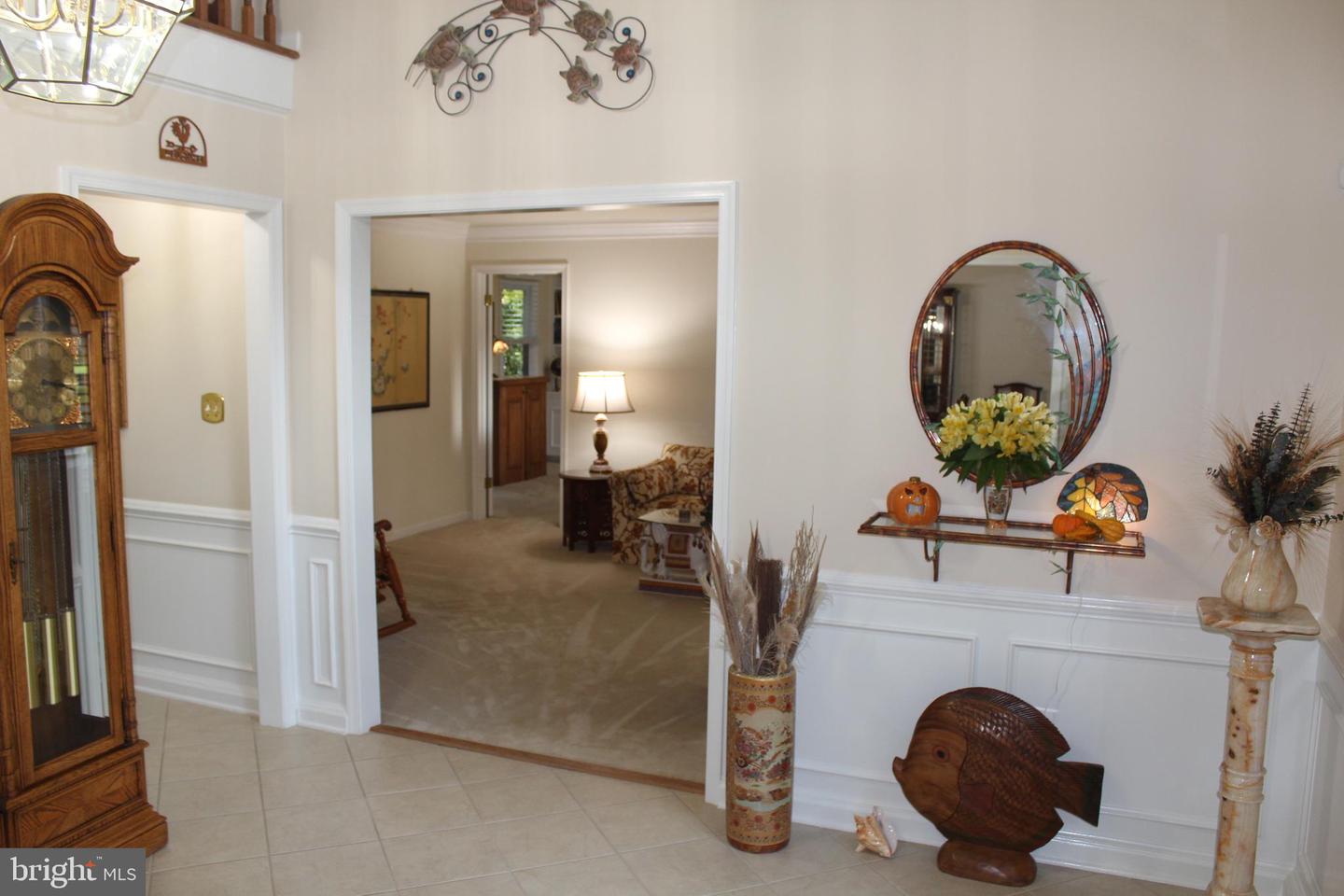 Furnished foyer with tiled floor, white wainscoting, and doorway into a carpeted sitting room.
