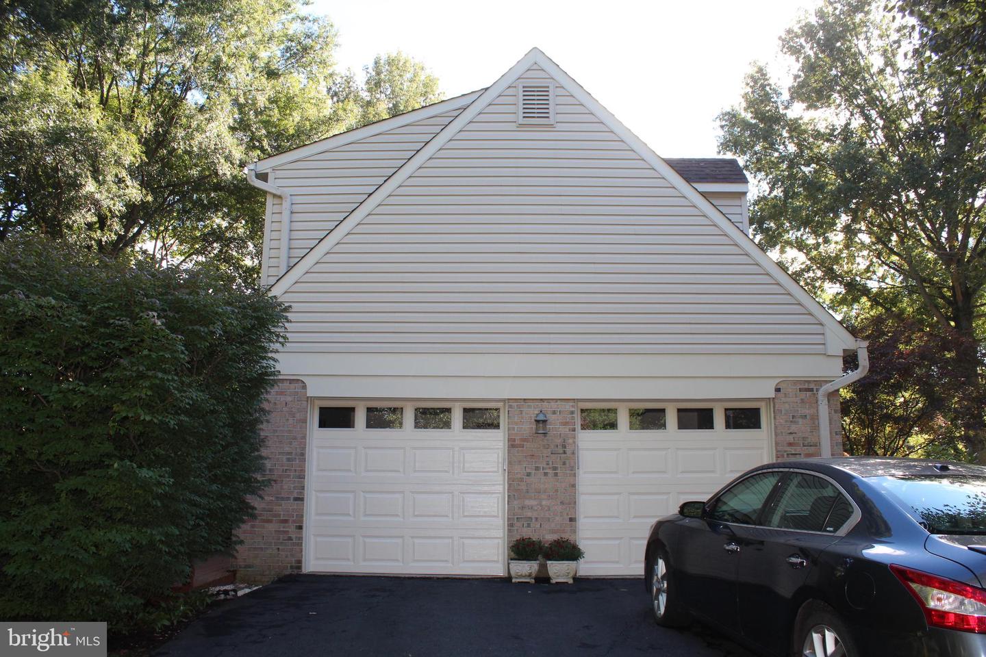 Home’s gabled garage facade with two white doors, brick accents, and a dark sedan in the driveway.
