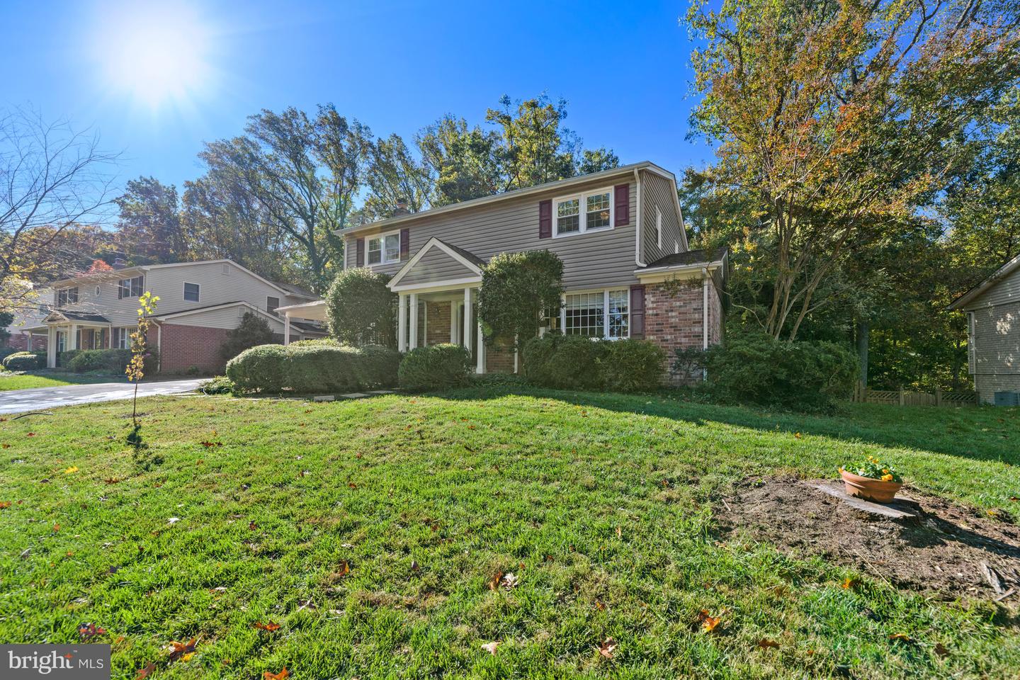 Two-story gray-sided home with brick accents, a covered entry, and a broad front lawn.