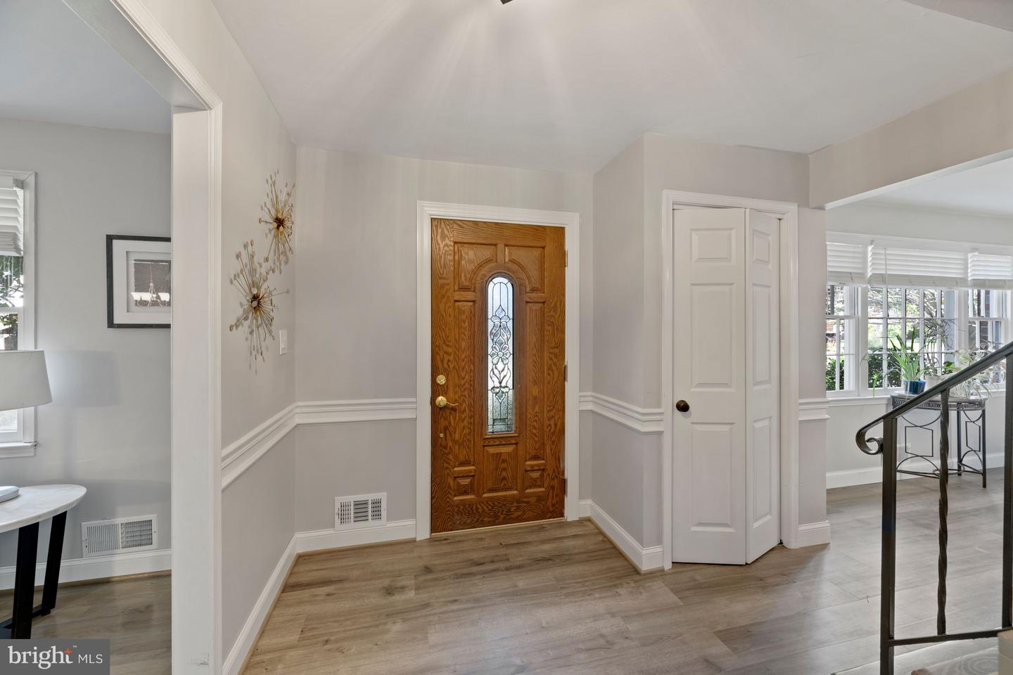 Entry foyer with a wood front door featuring a narrow decorative glass panel and a white double-door closet.