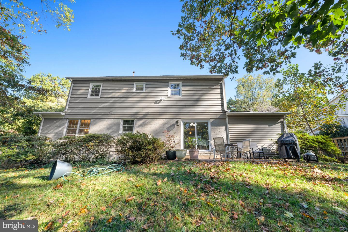 Rear of a gray two-story home with a brick lower level and backyard patio.