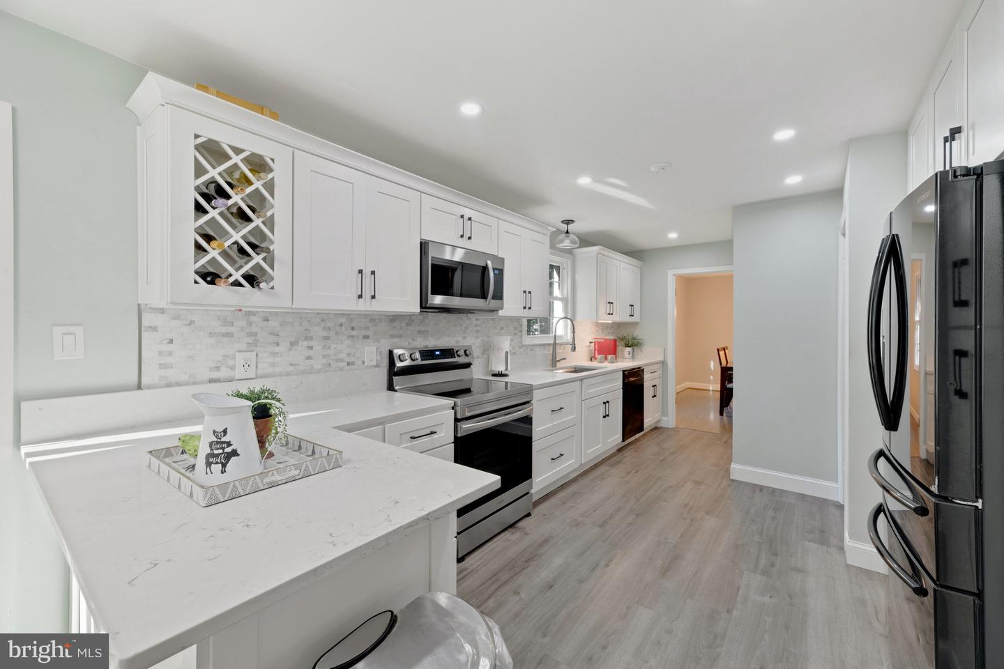 Renovated kitchen with white cabinets, stainless steel appliances, and a built-in wine rack.