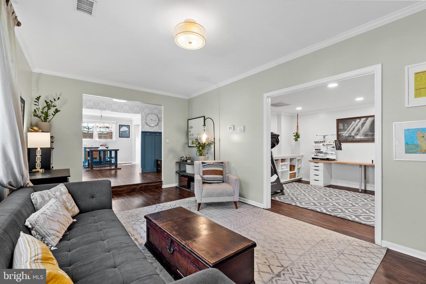 Living room with gray sectional, patterned rug, and adjoining bright workspace.