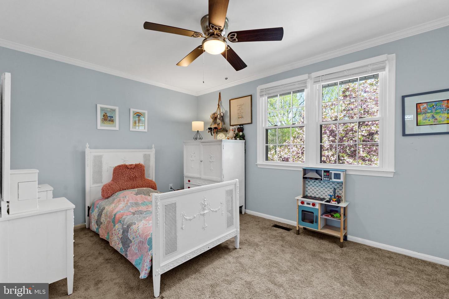 Furnished bedroom with an ornate white bed, pale blue walls, and two large windows.