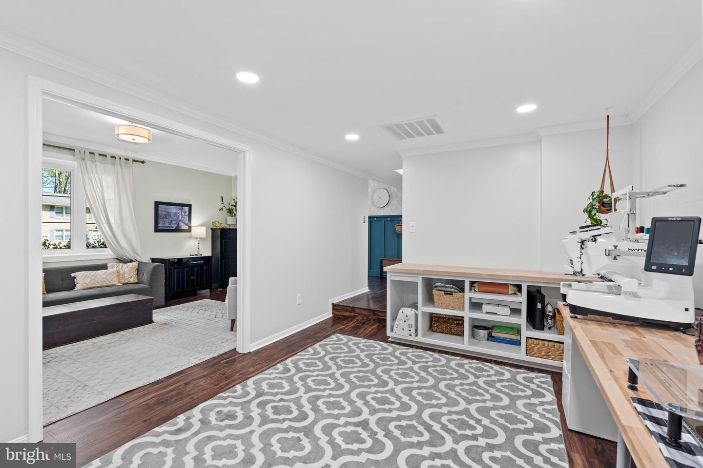 Workroom with an industrial sewing machine, built-in cubbies, and a patterned rug beside the living room.