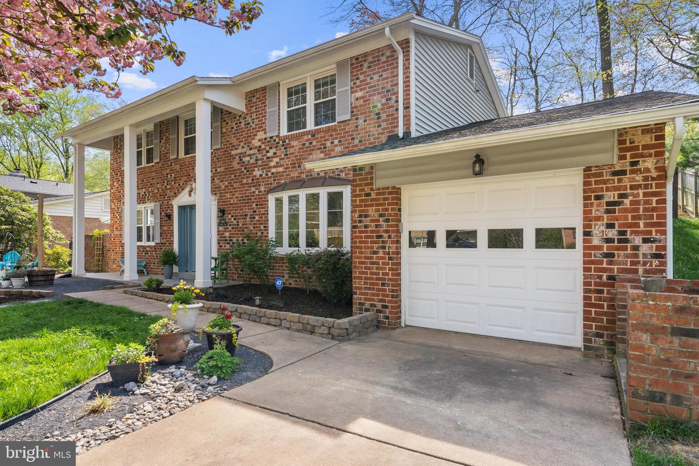 Two-story brick house with a covered entry, attached garage, and landscaped front yard.