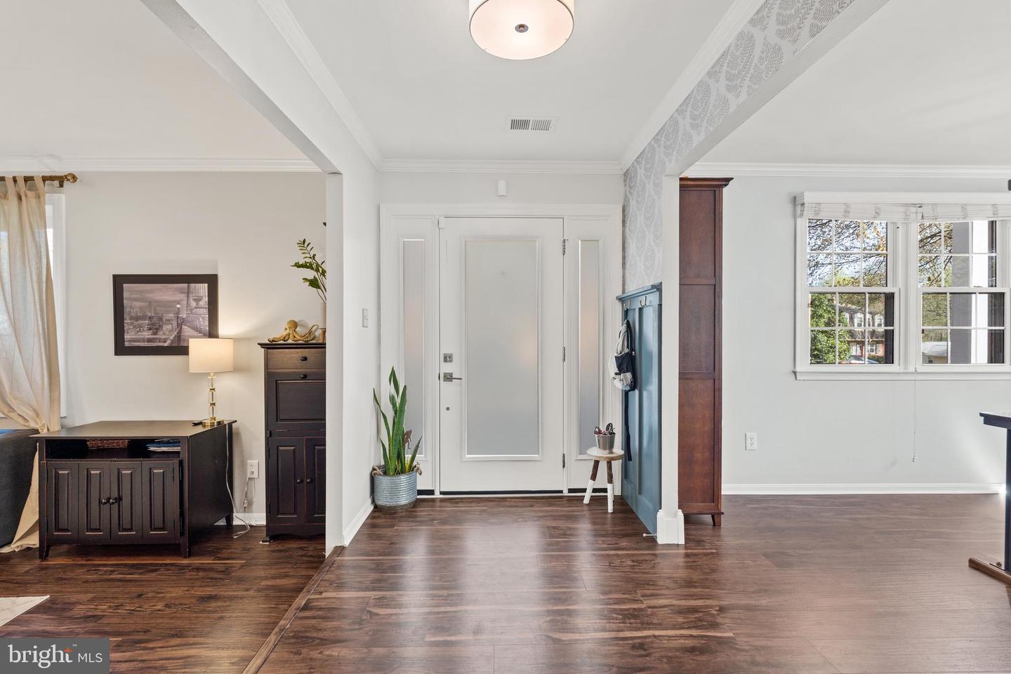 Furnished entryway with a white front door, blue coat area, and dark wood floors.