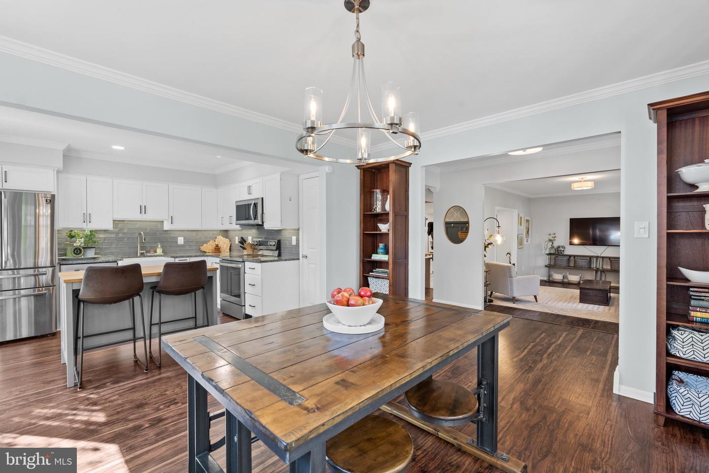Open kitchen and dining area with white cabinets, stainless appliances, and a rustic wood island.