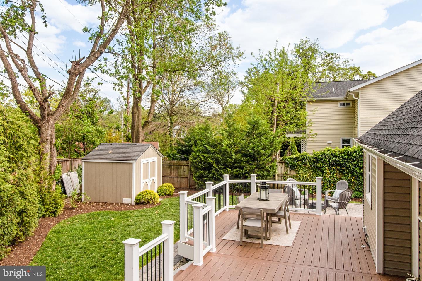 Backyard deck with white railings, outdoor dining set, and a view of the lawn and shed.