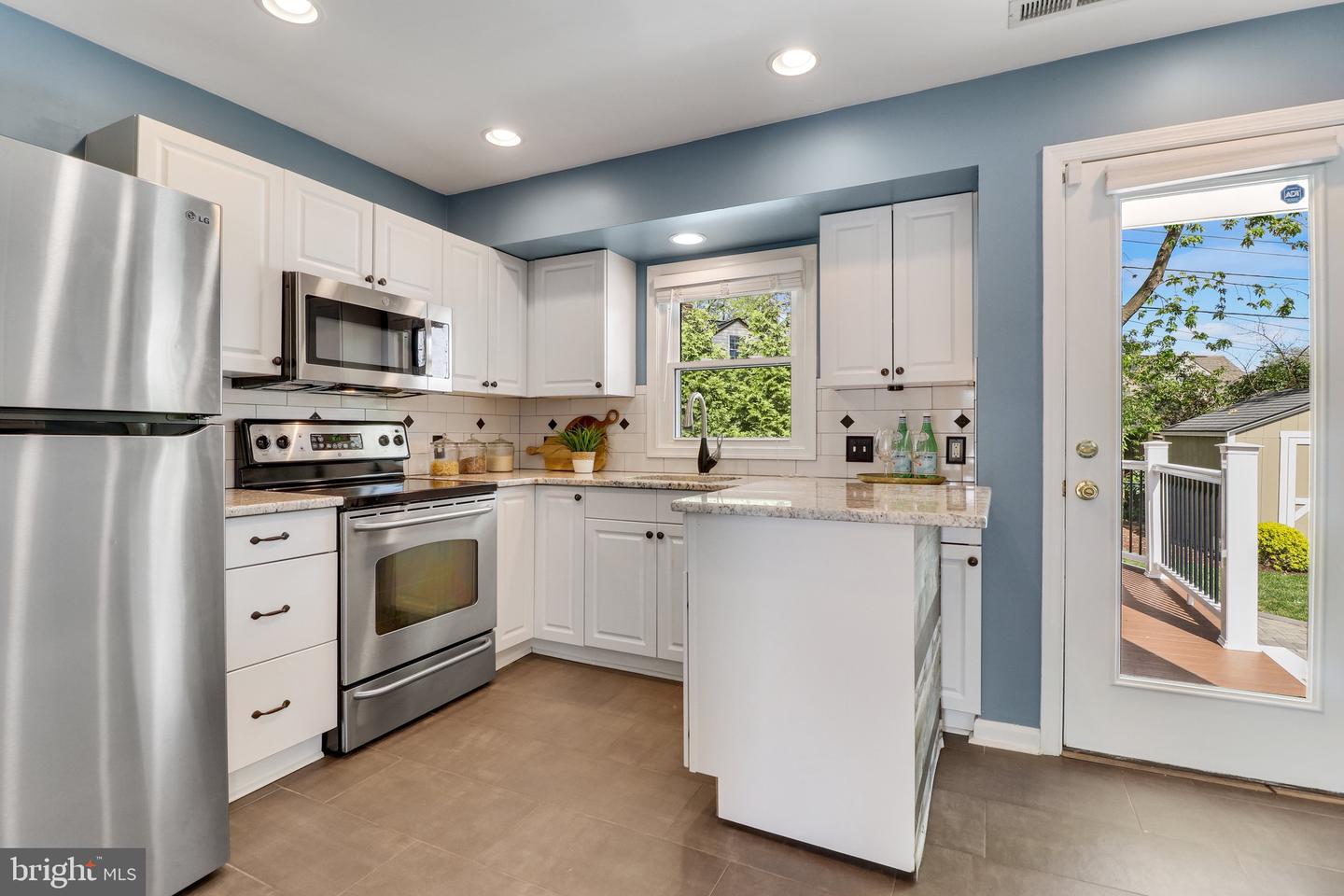 Kitchen with white cabinets, stainless steel appliances, blue walls, and a glass door opening to a deck.