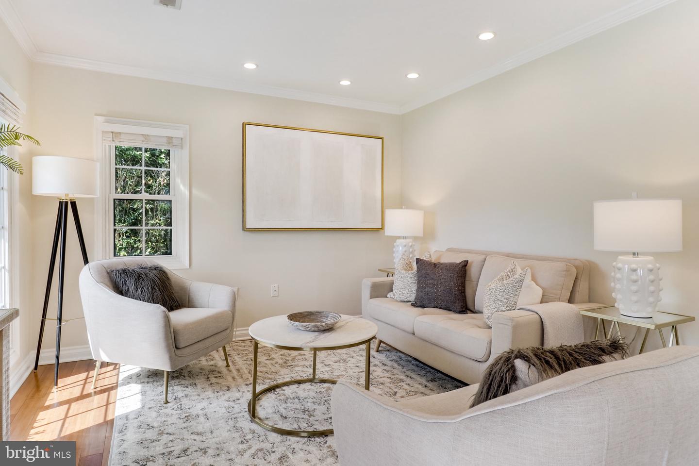 Staged living room with cream seating, a round coffee table, and sunlight through the windows.