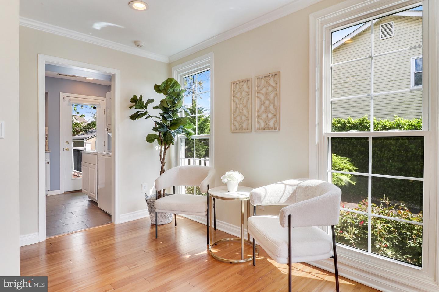 Bright sitting area with two upholstered chairs, hardwood floors, and large windows.