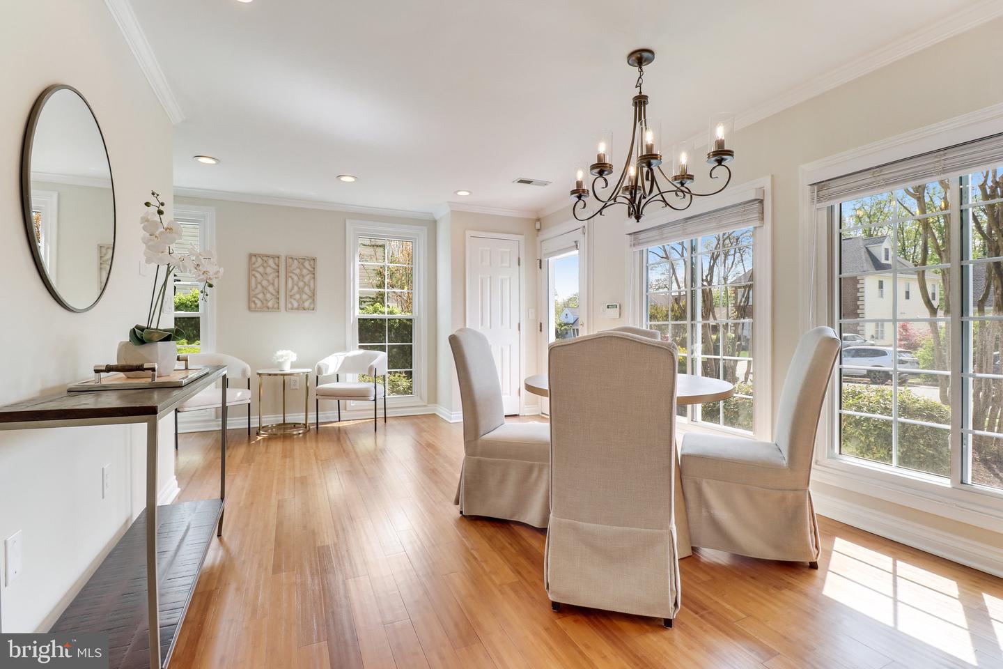 Dining room with hardwood floors, upholstered chairs, chandelier, and large windows overlooking the street.