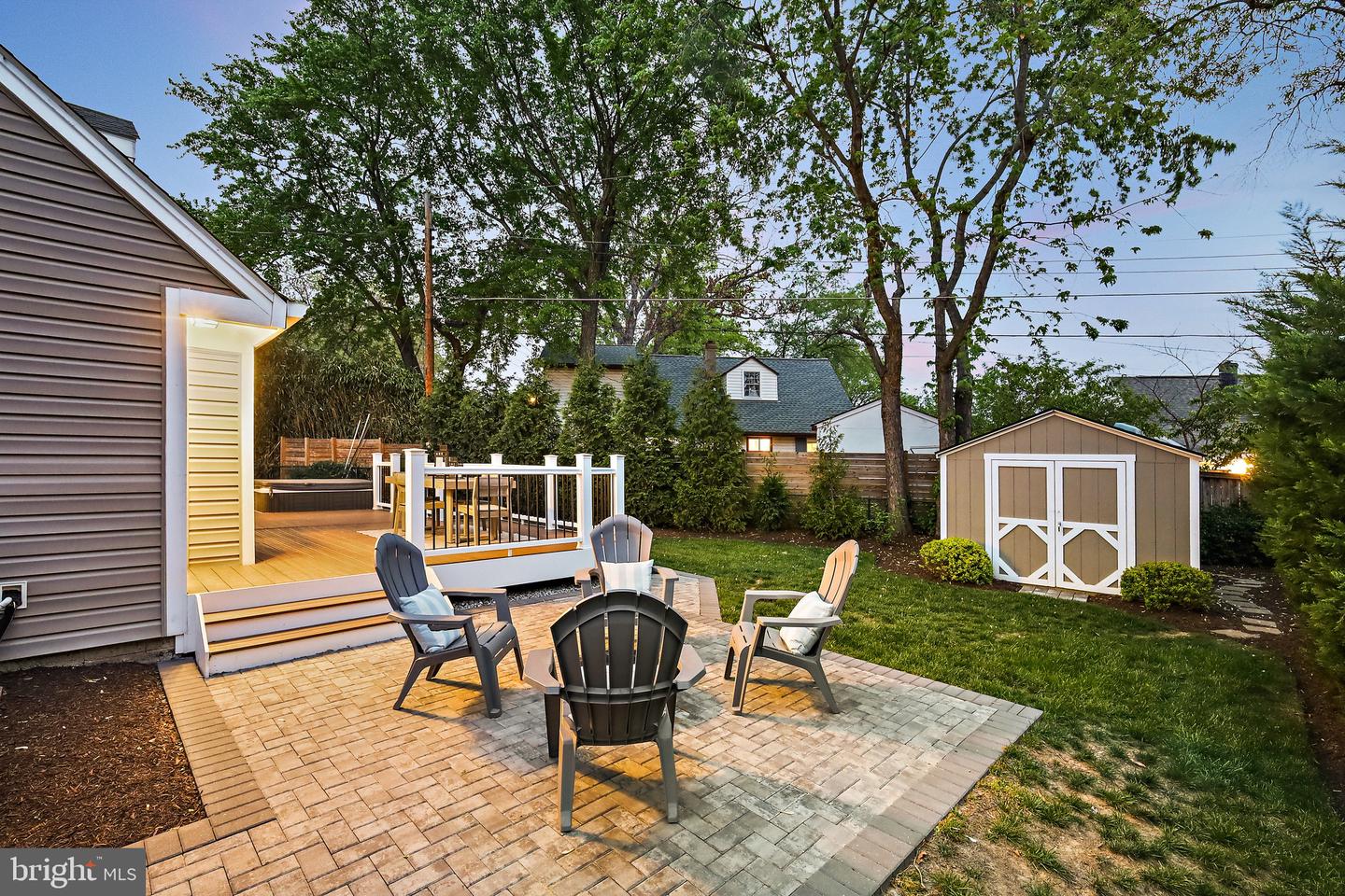 Backyard patio with Adirondack chairs, raised deck, hot tub, and shed.