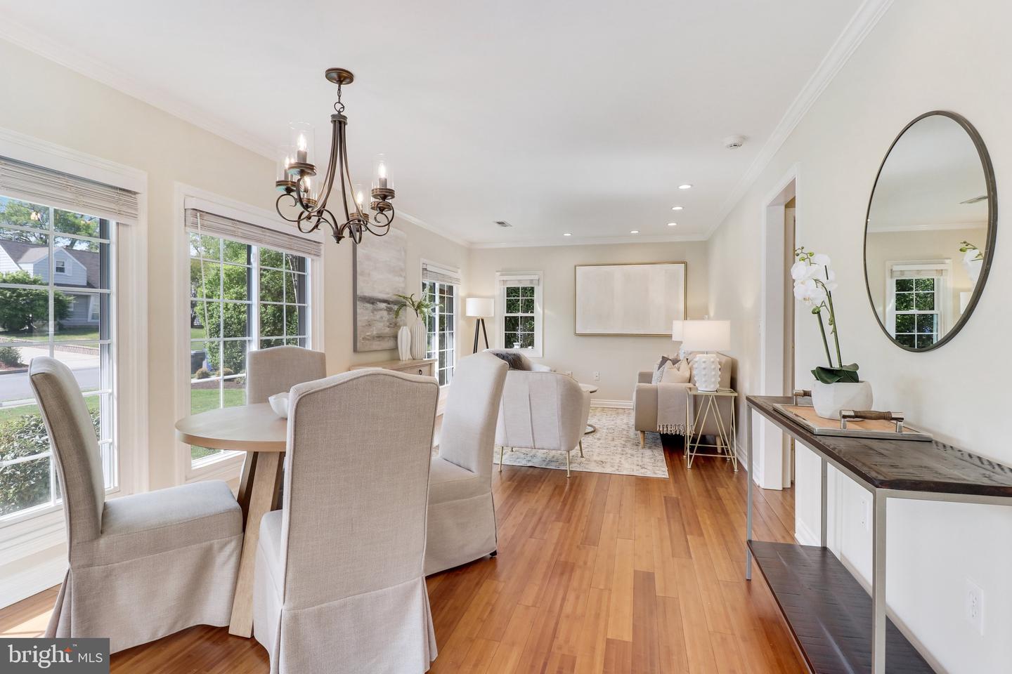 Staged dining and sitting area with hardwood floors, large windows, and a chandelier.