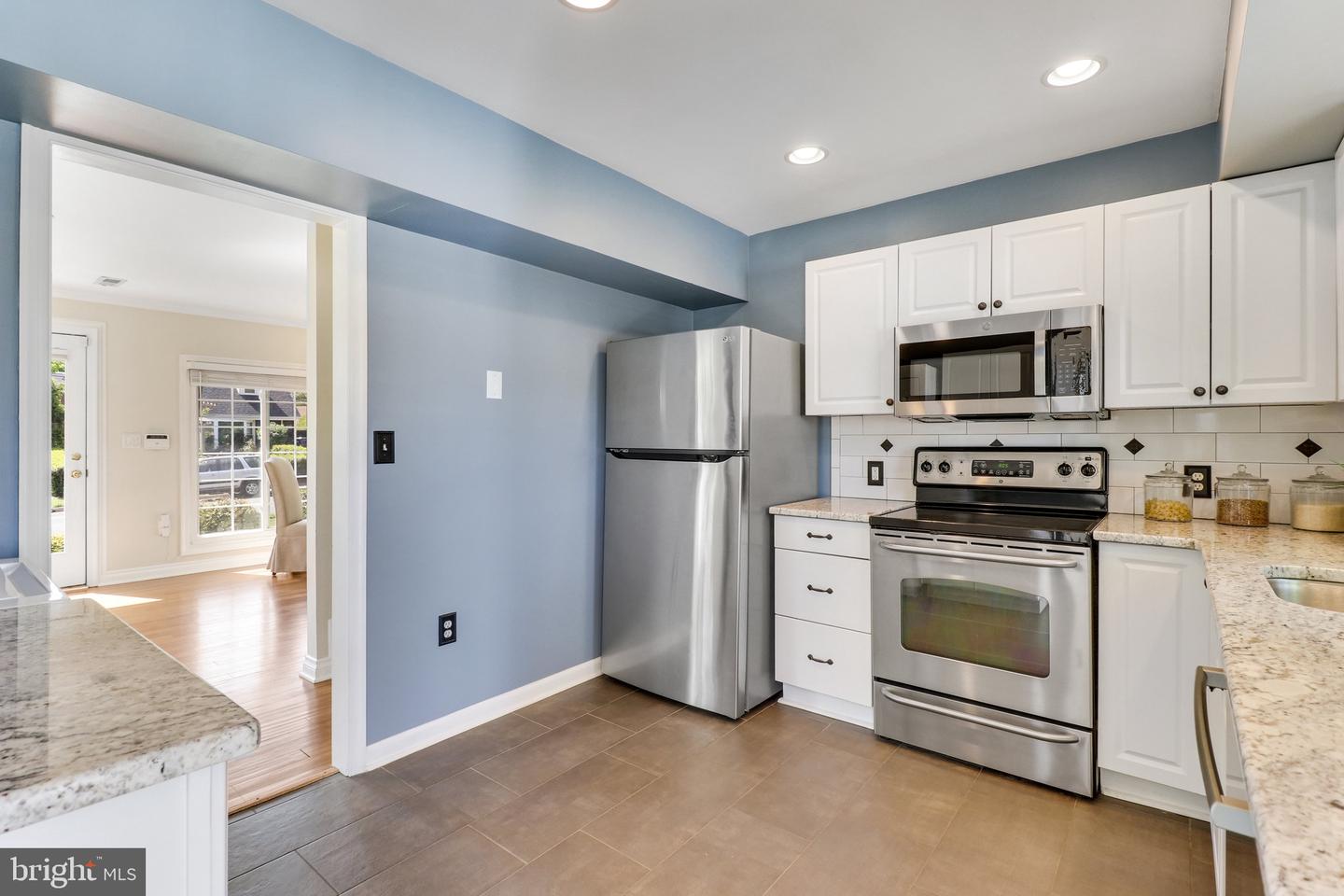 Kitchen with blue walls, white cabinets, granite counters, and stainless steel appliances.