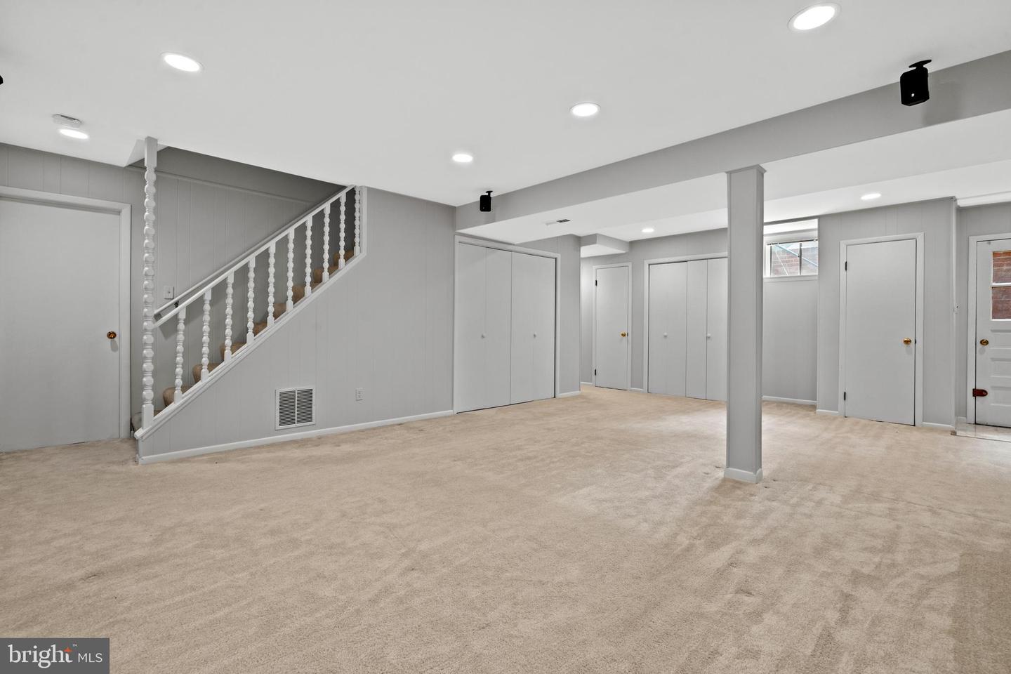 Unfurnished carpeted lower-level room with a staircase, multiple closets, and recessed lighting.