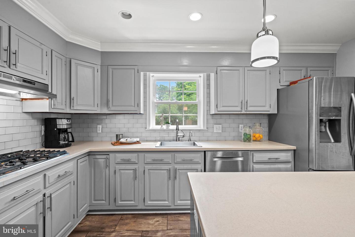 Kitchen with gray cabinets, stainless steel appliances, subway tile backsplash, and a large island.