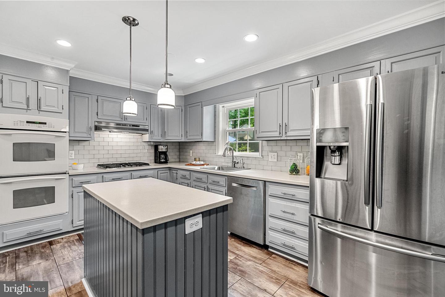 Renovated kitchen with gray cabinets, a large island, subway-tile backsplash, and stainless steel appliances.
