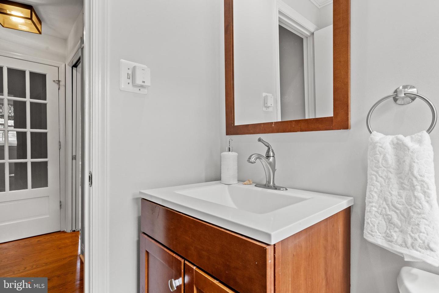 Bathroom vanity with a white sink, wood cabinetry, and a matching framed mirror.