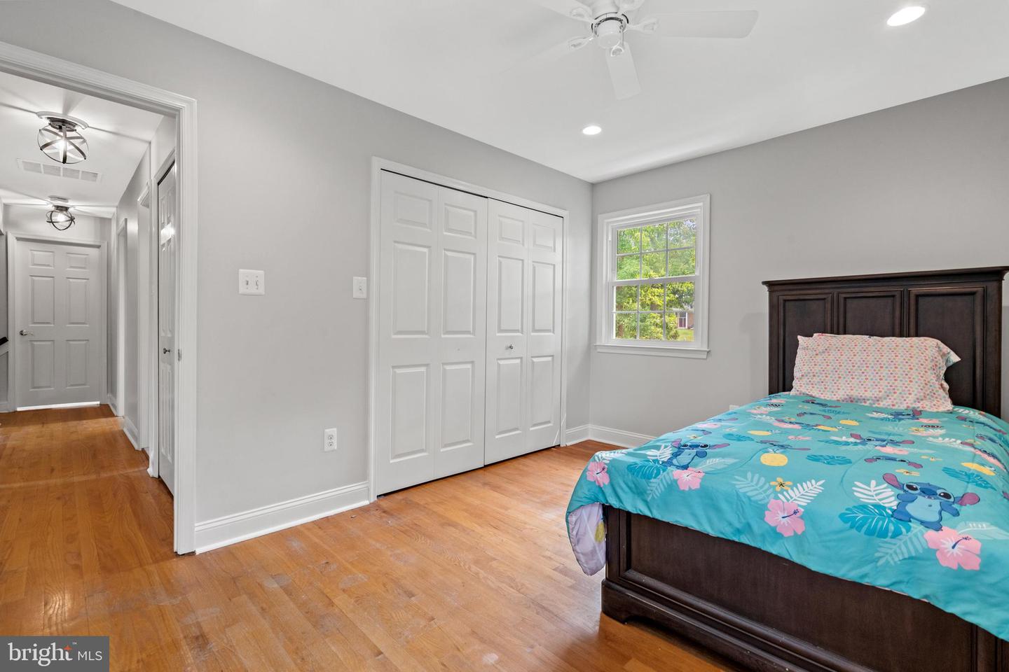 Bedroom with a dark wood bed, turquoise comforter, hardwood floors, and white closet doors.