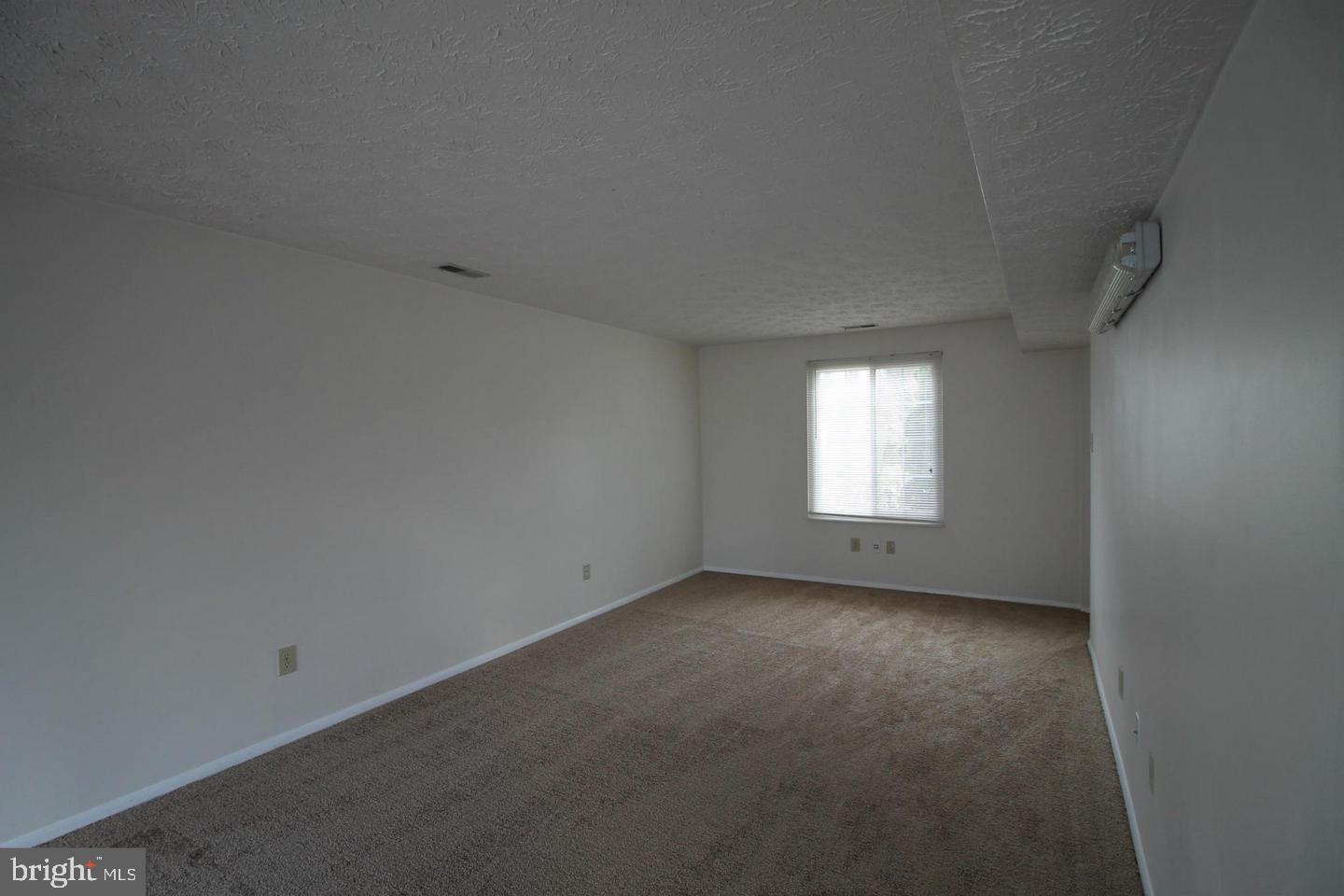 Empty carpeted room with white walls and a window with blinds.