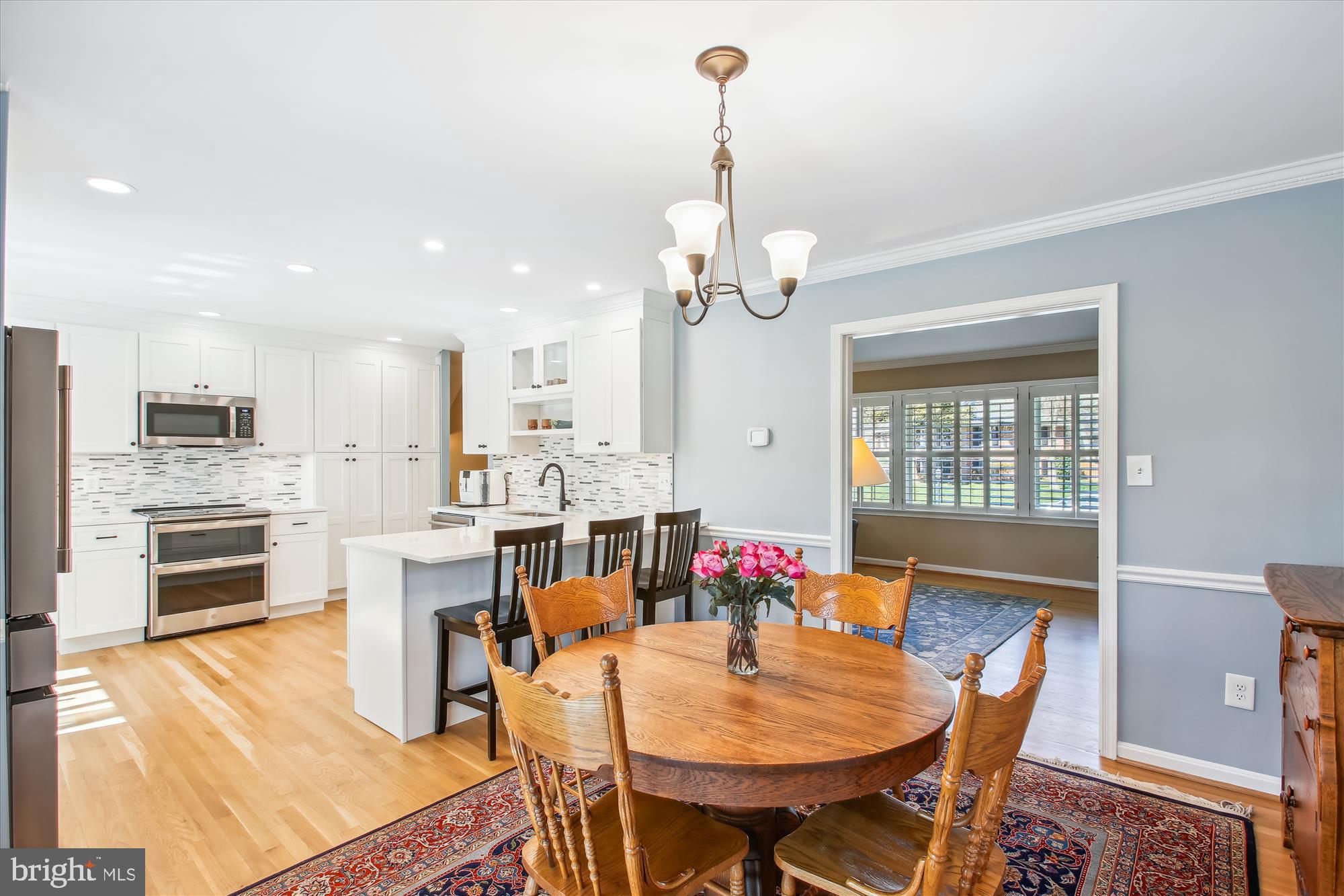 Open kitchen and dining area with white cabinetry, an island, and a round wooden table on a patterned rug.