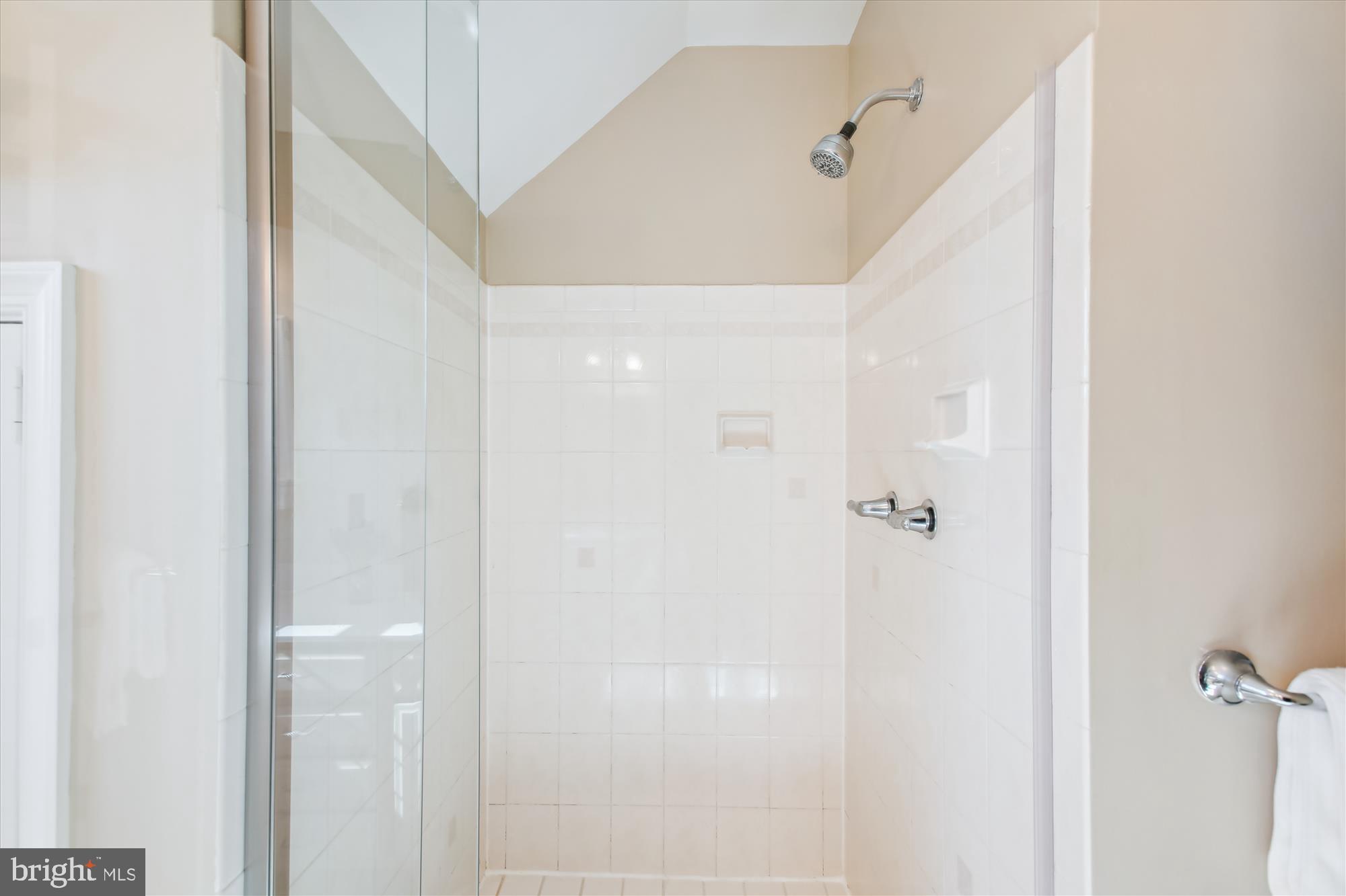White-tiled walk-in shower with a clear glass enclosure and chrome fixtures.