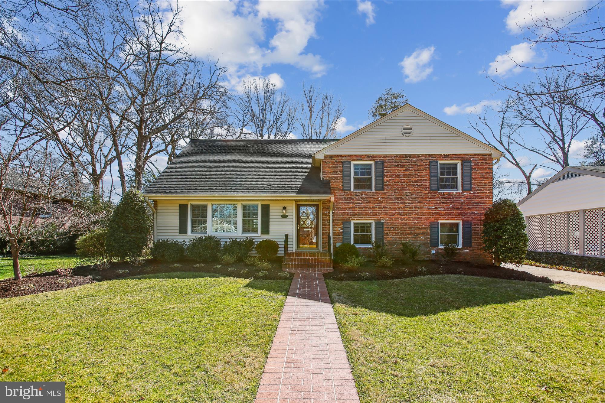 Two-story brick-and-siding home with a brick walkway leading to the front entrance.