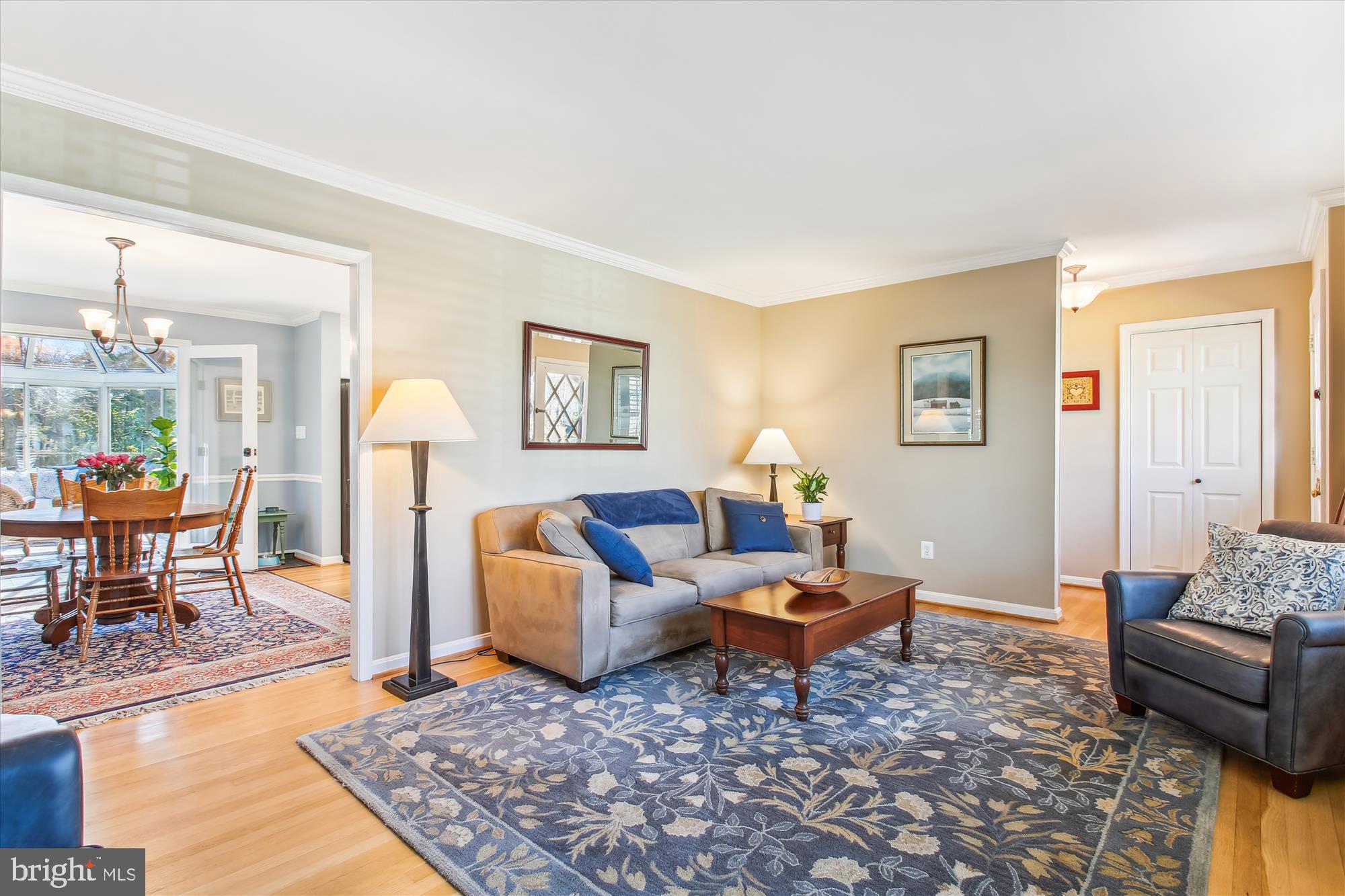 Living room with a gray sofa and blue pillows beside an adjoining dining room.