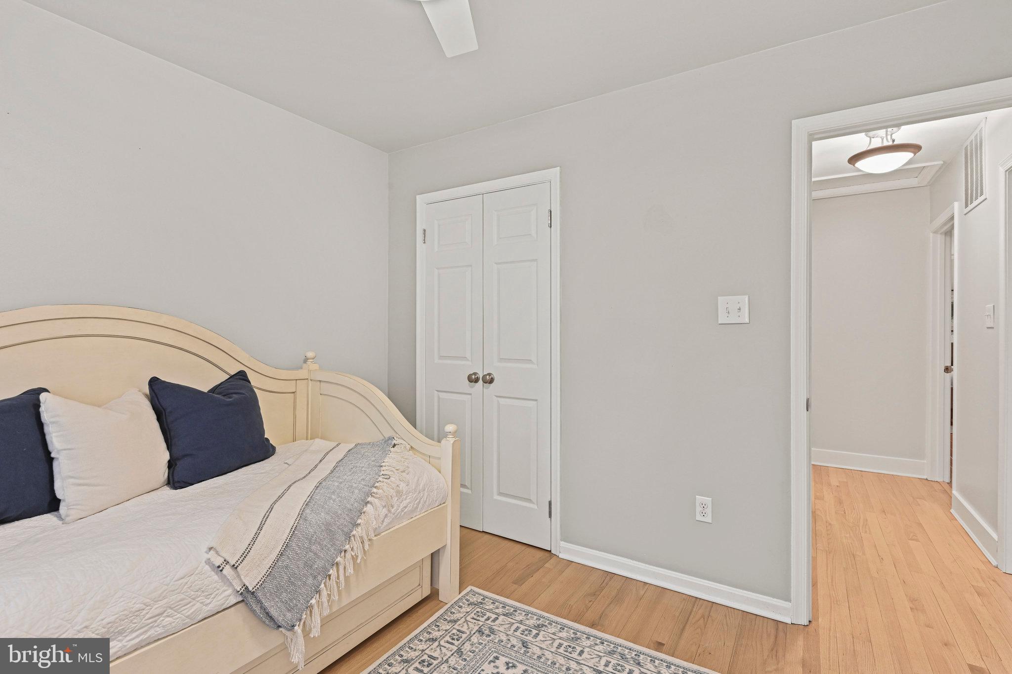 Bedroom with a cream bed, navy pillows, patterned throw, and white double closet doors.