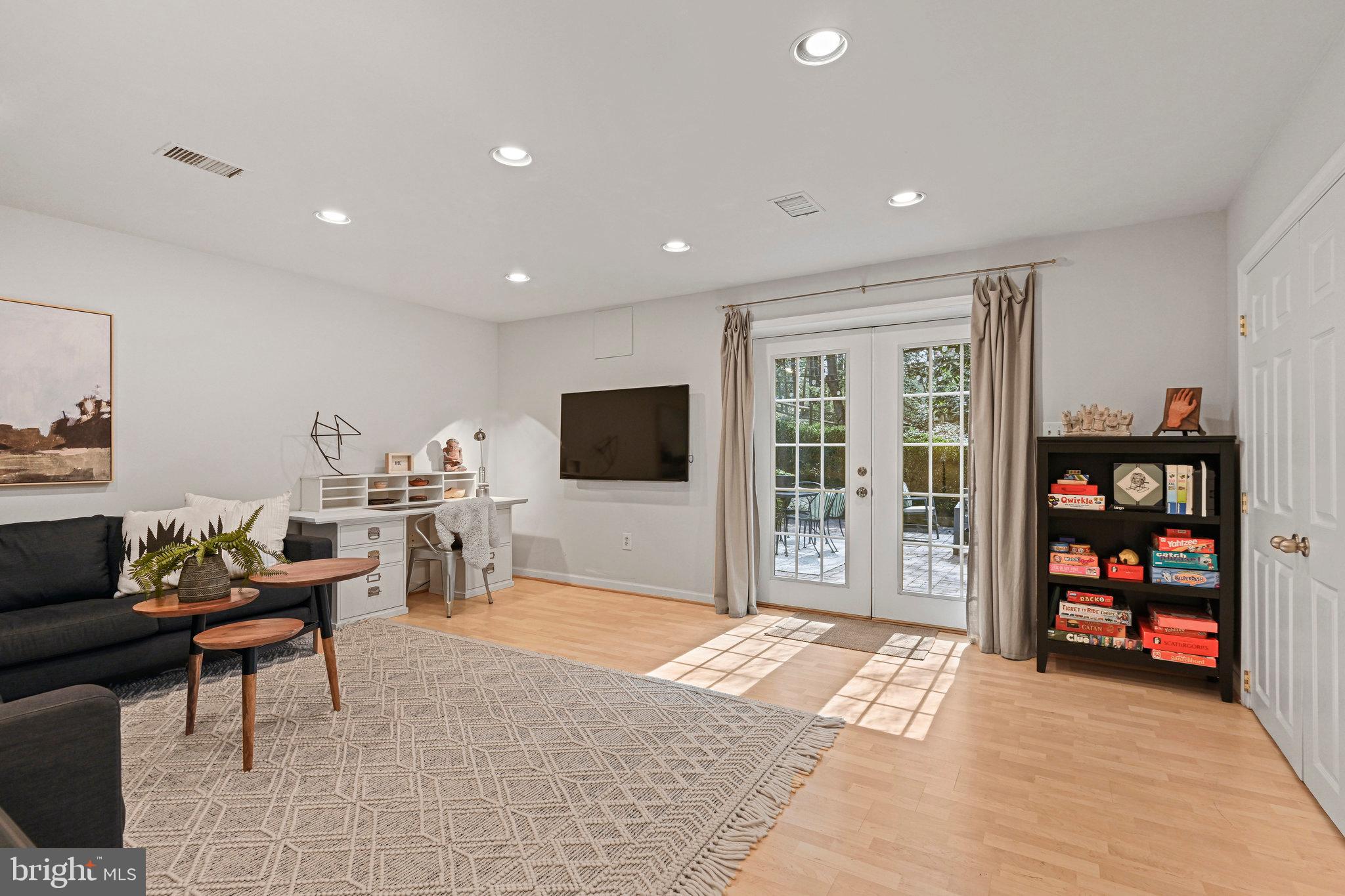 Furnished living room with a wall-mounted TV, game shelf, and glass-paneled patio doors.
