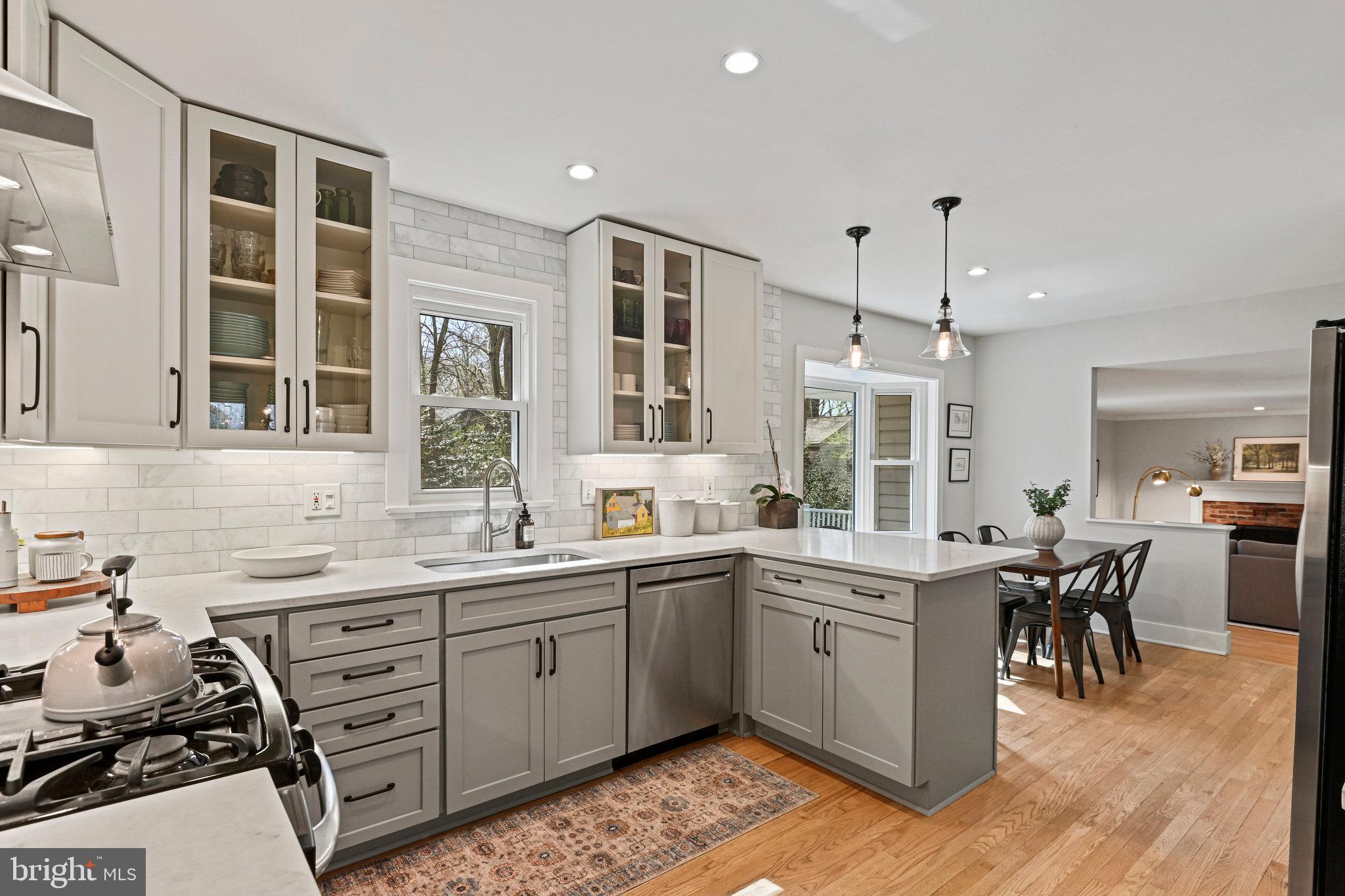 Kitchen with gray cabinets, white subway-tile backsplash, central island, and adjoining dining area.