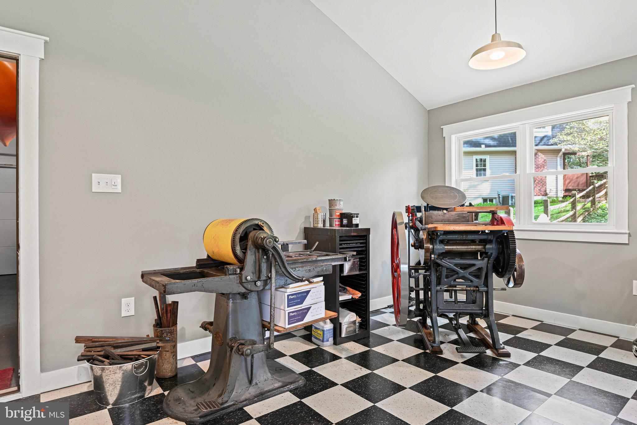 Printmaking workshop with two vintage presses and a black-and-white checkerboard floor.