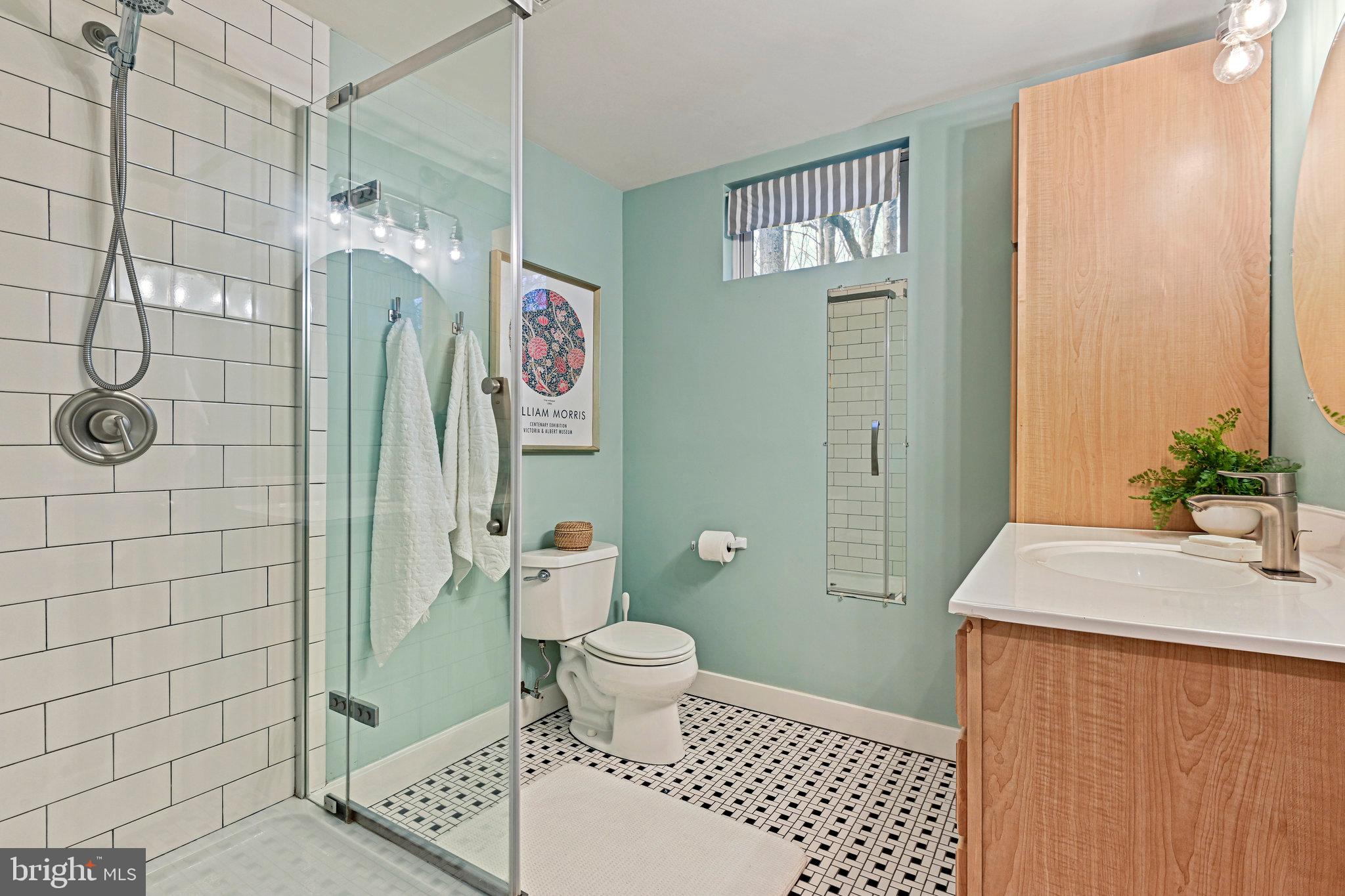 Bathroom with a glass shower, mint walls, mosaic tile floor, and wood-front vanity.