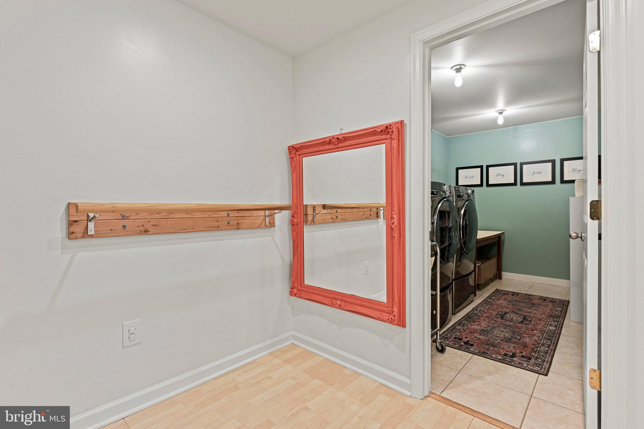 Laundry room with front-loading washer and dryer, mint-green walls, and a patterned rug.